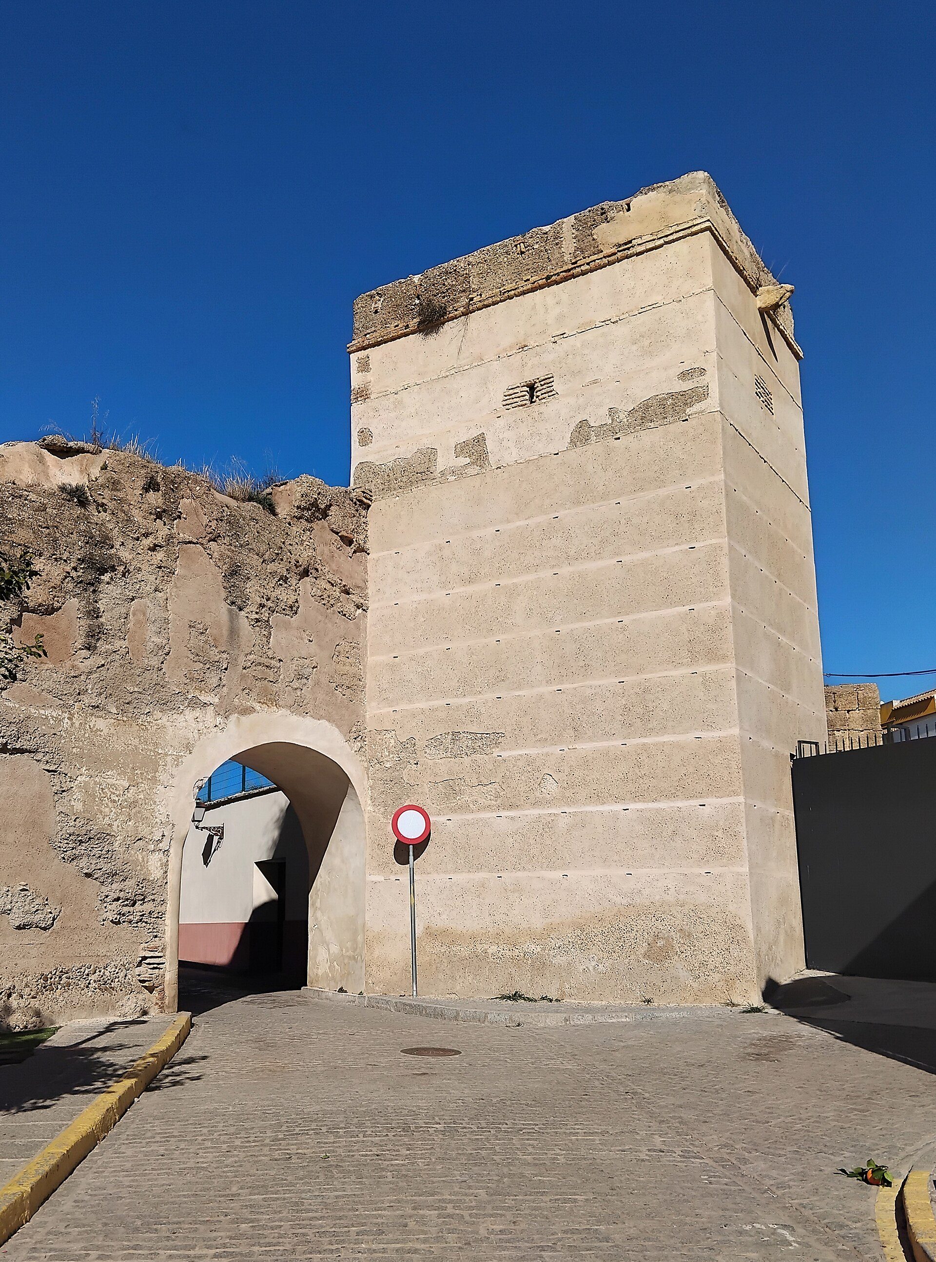 A stone tower with an arched entrance, set against a clear blue sky.