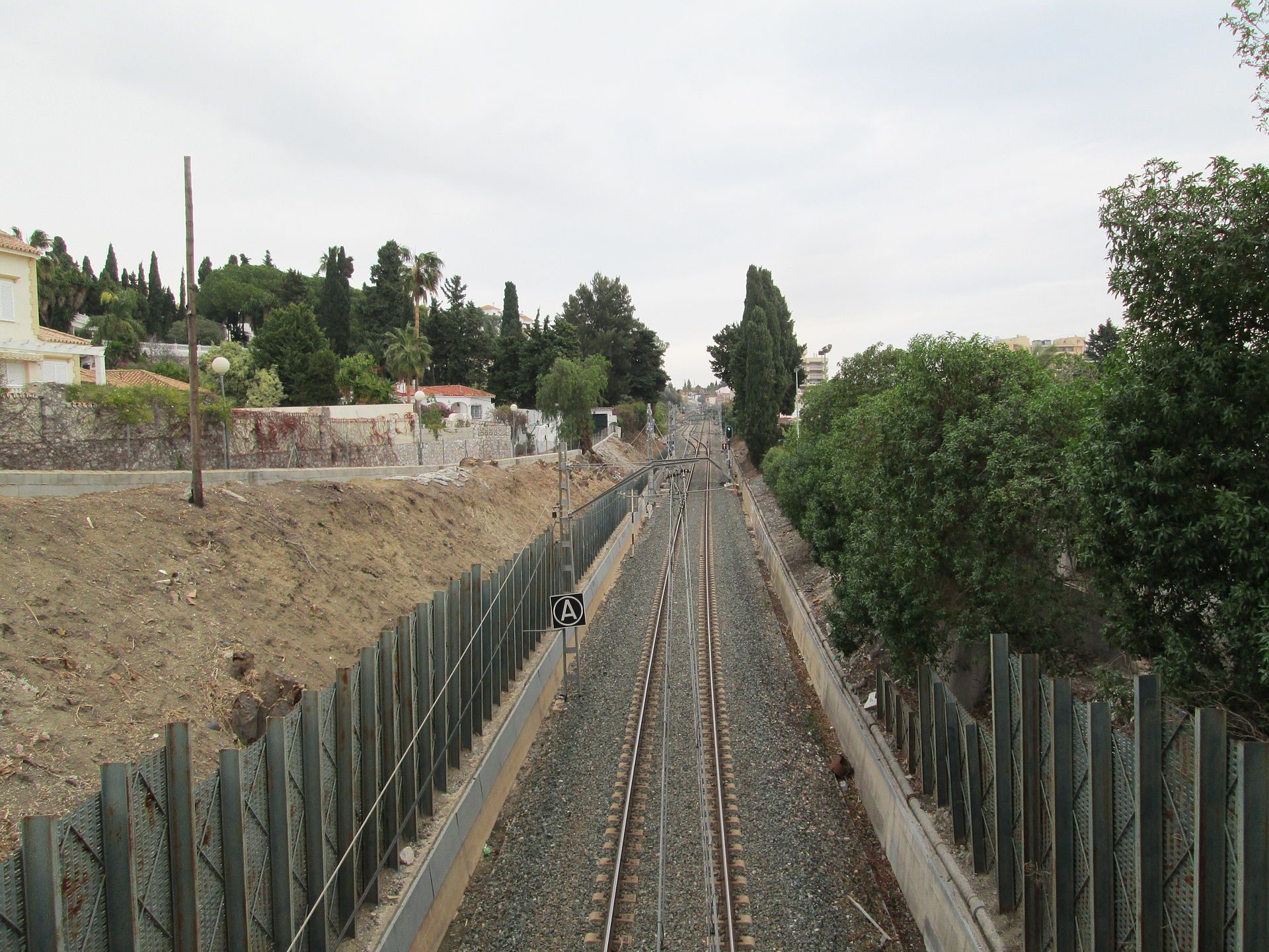 Alt text: "Railway track view with greenery and trees on both sides.