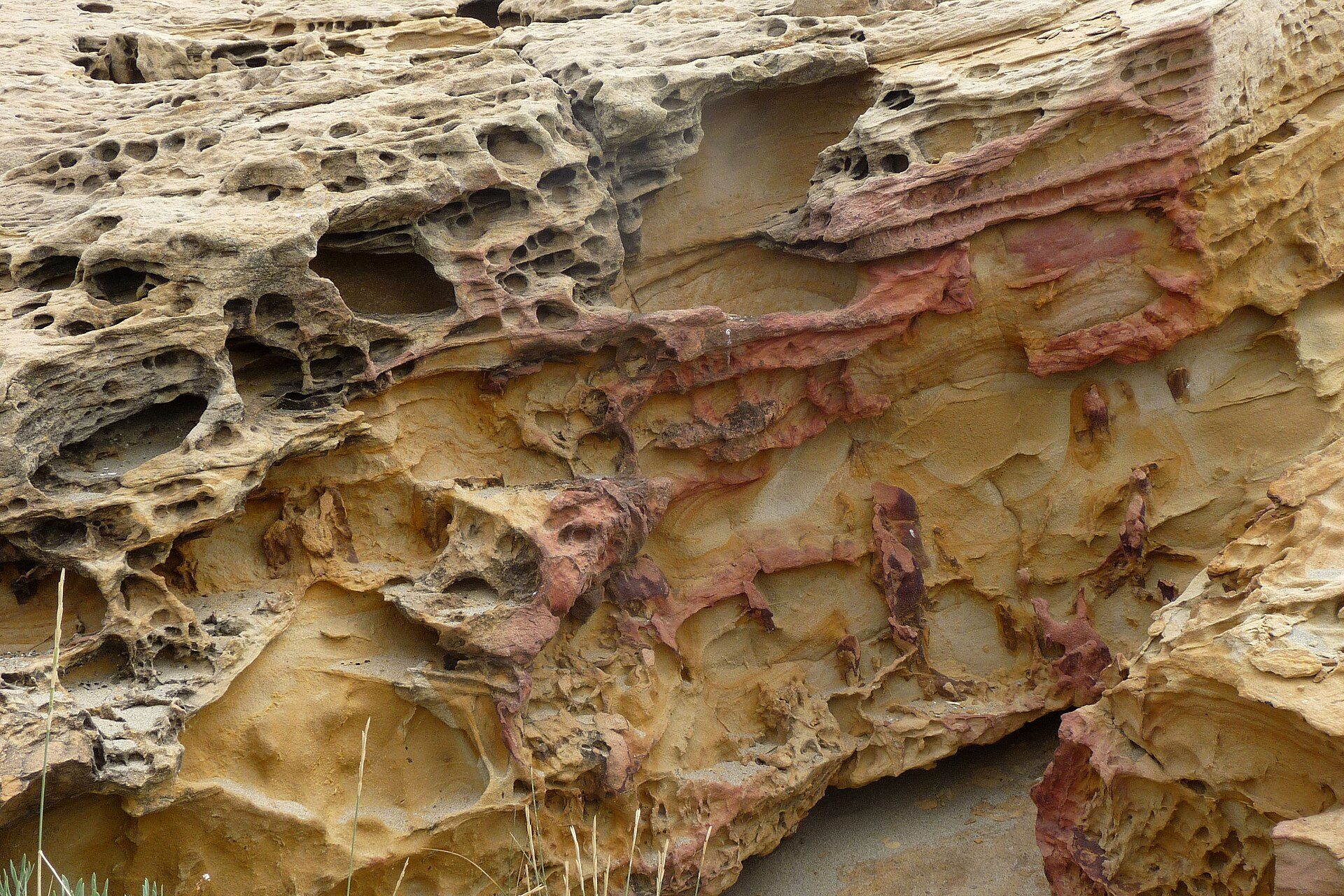 Rocky cliff face with natural erosion patterns and reddish-brown mineral deposits.