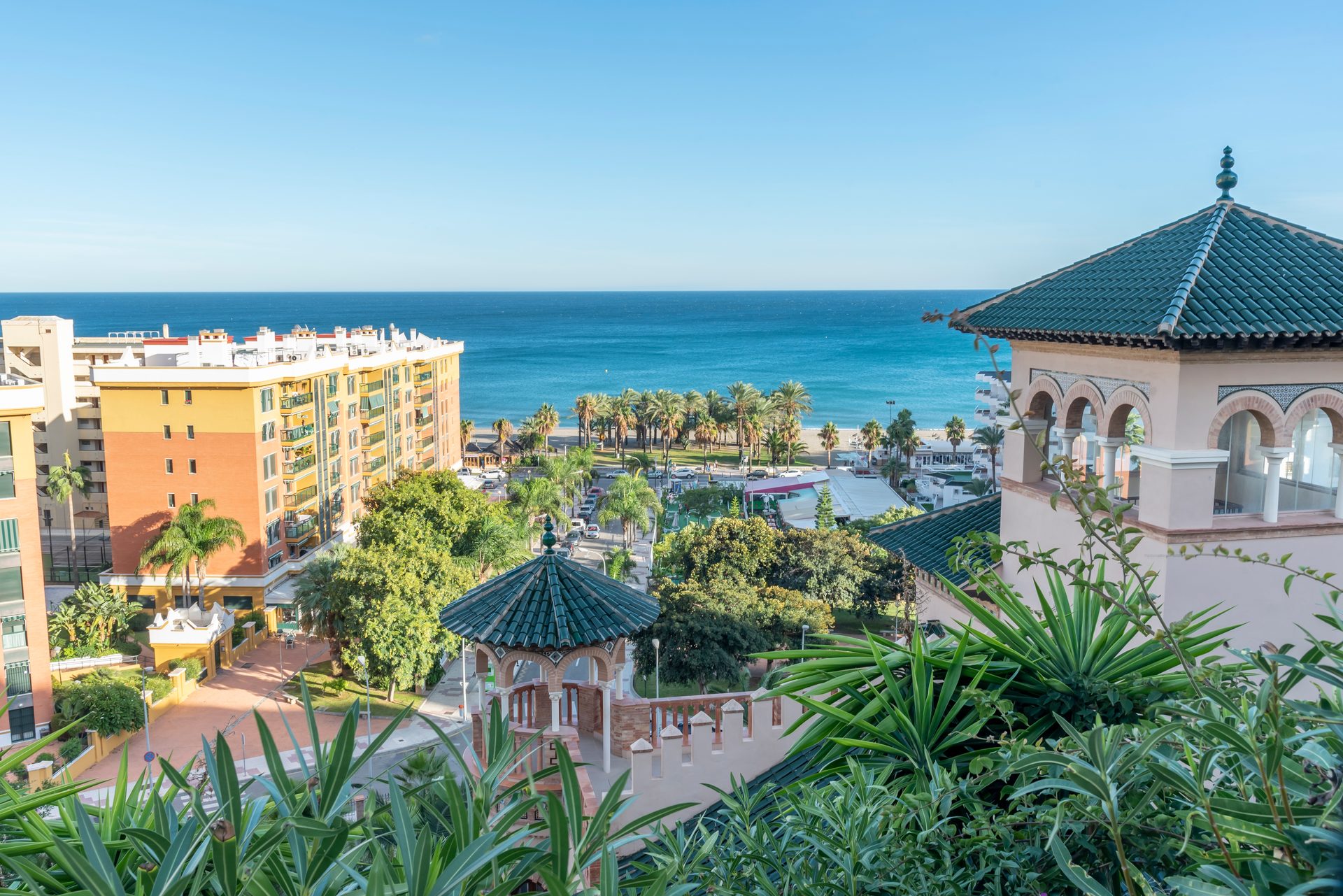 Oceanfront hotel room with balcony, sea view, pool, and lush gardens.
