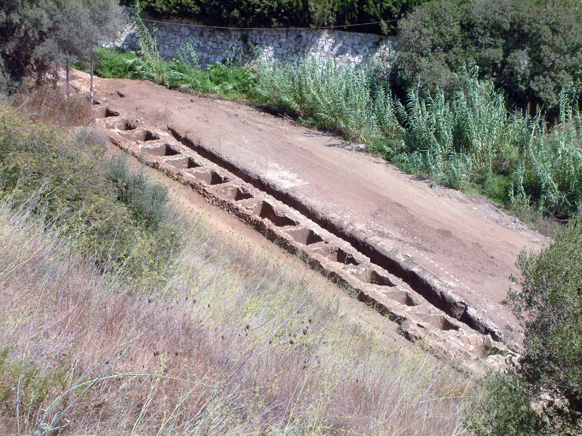 Alt text: Outdoor terrace with stone seating, overlooking a lush garden and stone wall.