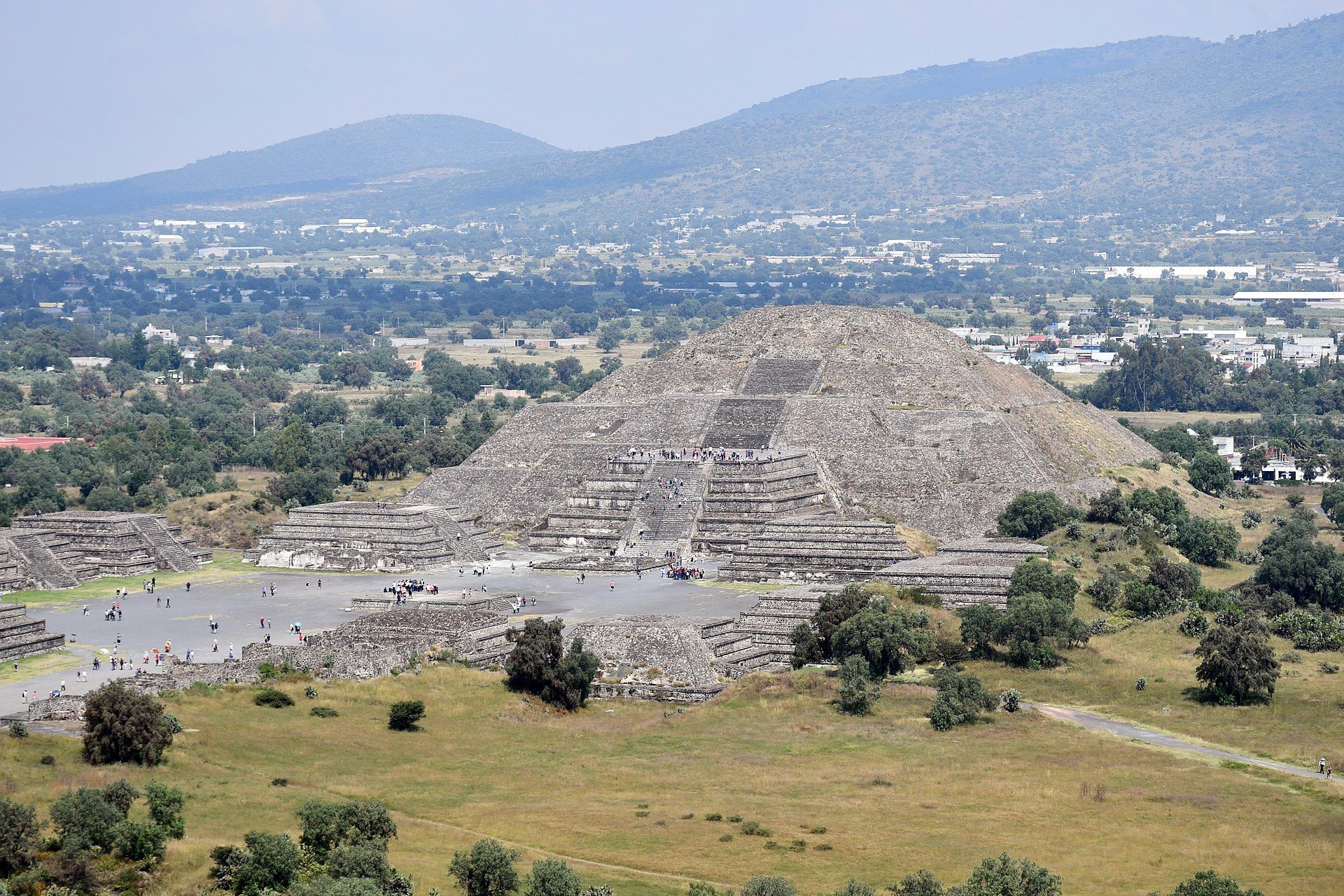 Alt text: Panoramic view of ancient pyramid ruins with surrounding greenery and distant mountains.