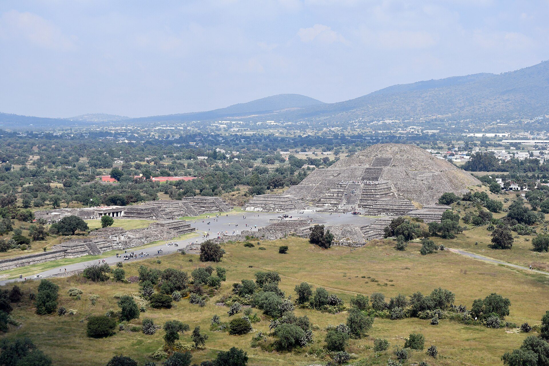 Alt text: Panoramic view of ancient pyramid ruins with surrounding greenery and distant mountains.