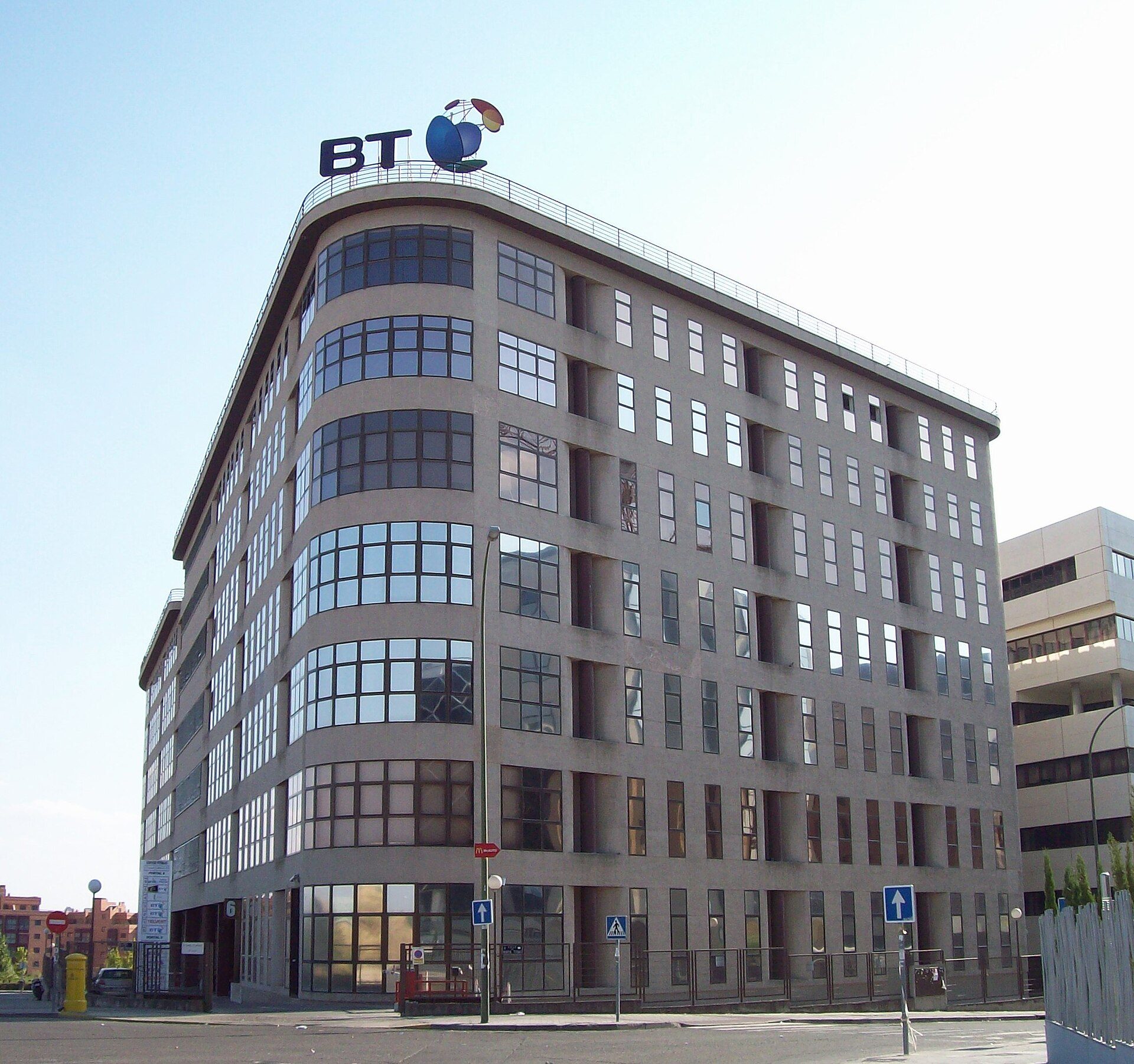 Modern office building with large windows, curved facade, and BT logo.