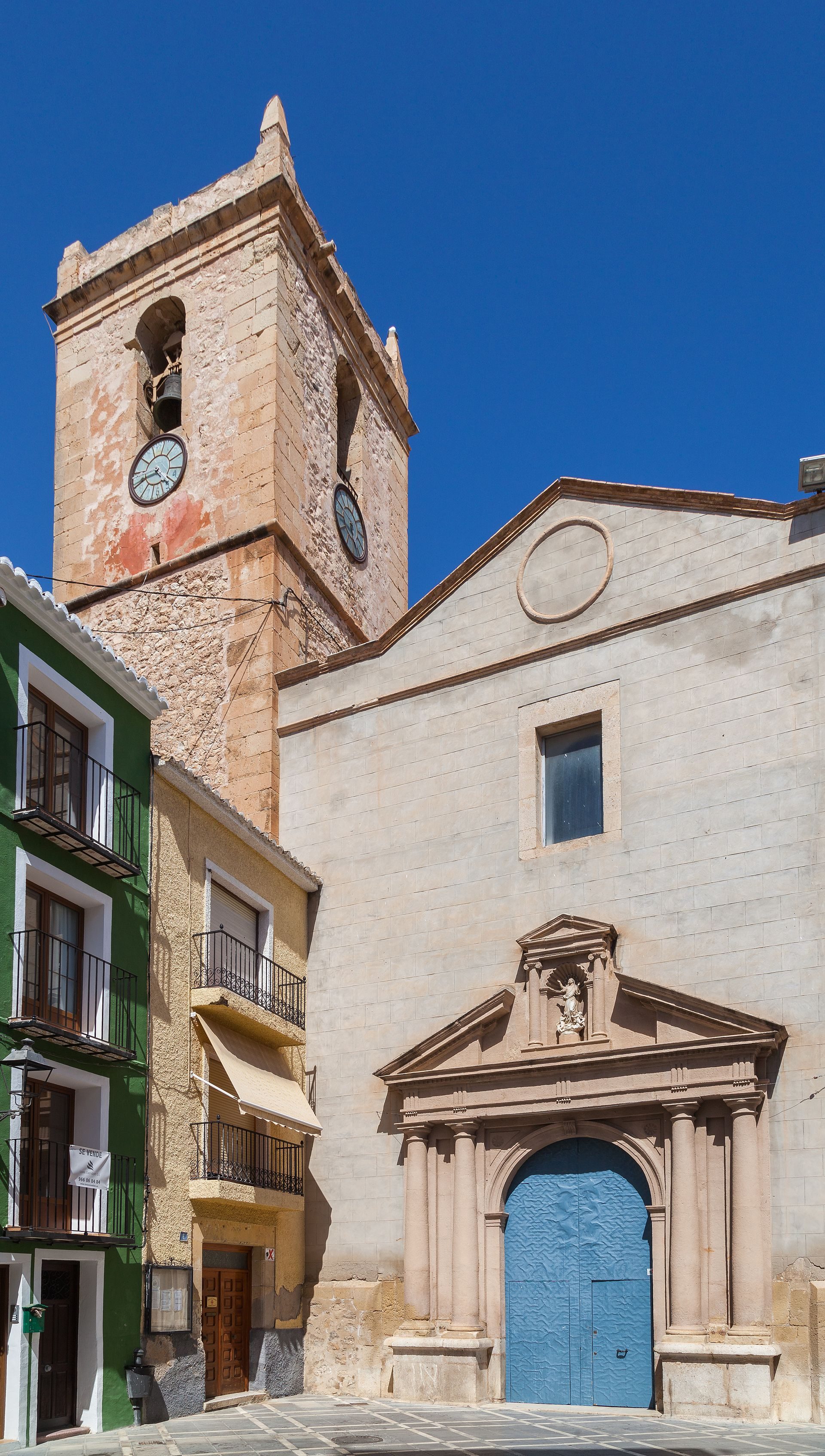 Traditional building with a clock tower, stone facade, and blue door.