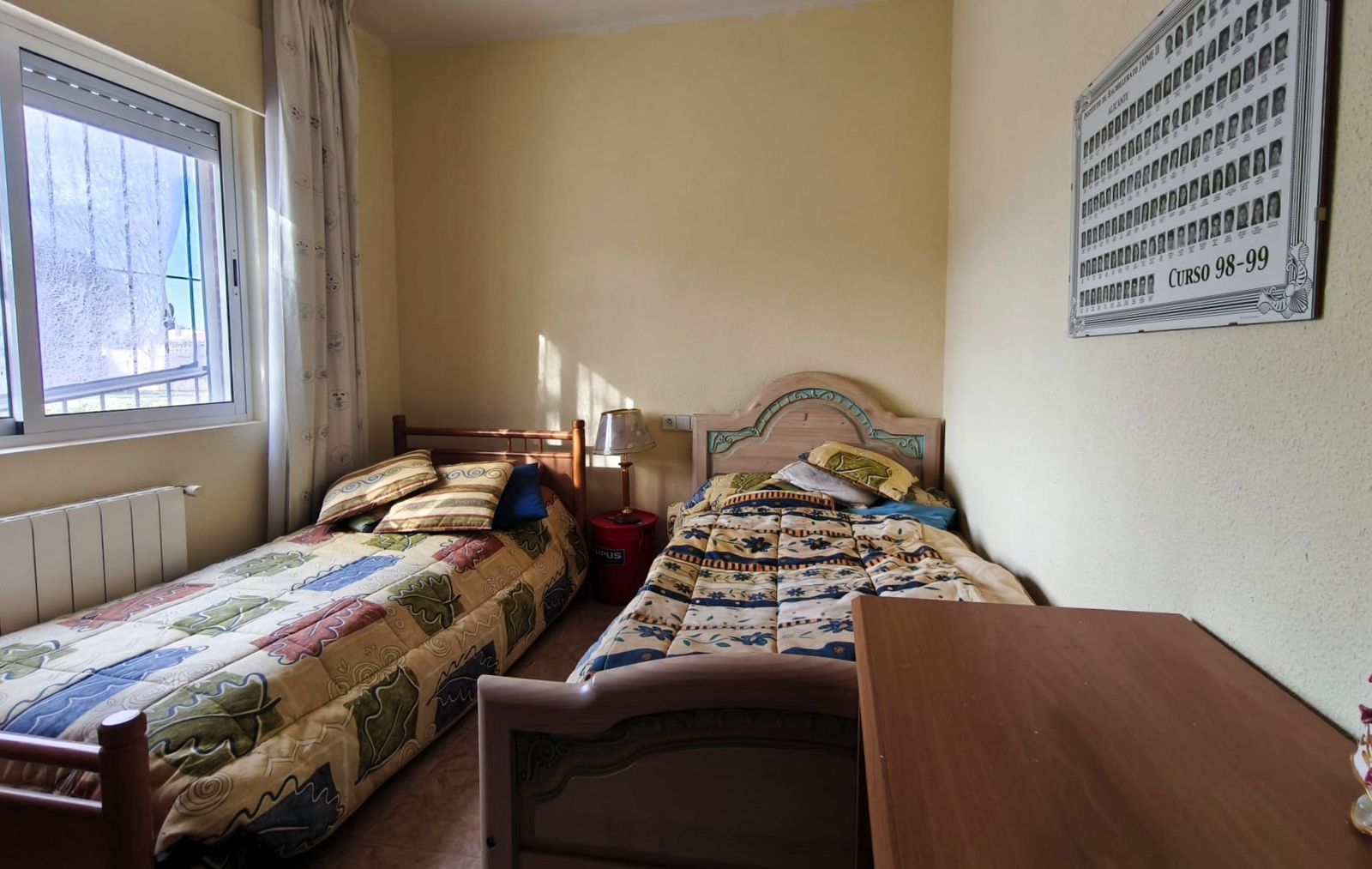 Kleine slaapkamer met twee eenpersoonsbedden en een raam.