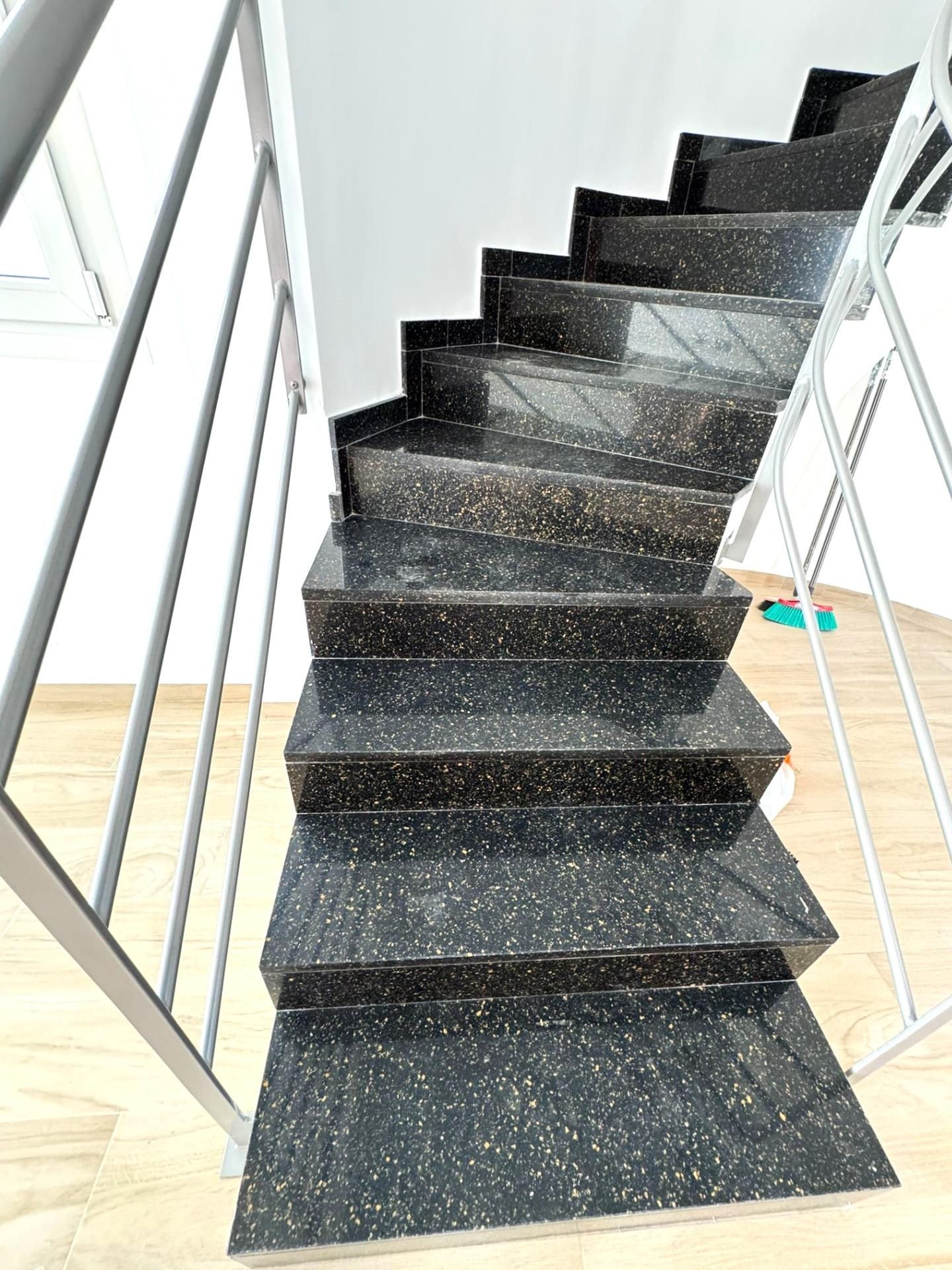 Moderne trap met zwart graniet en metalen leuning