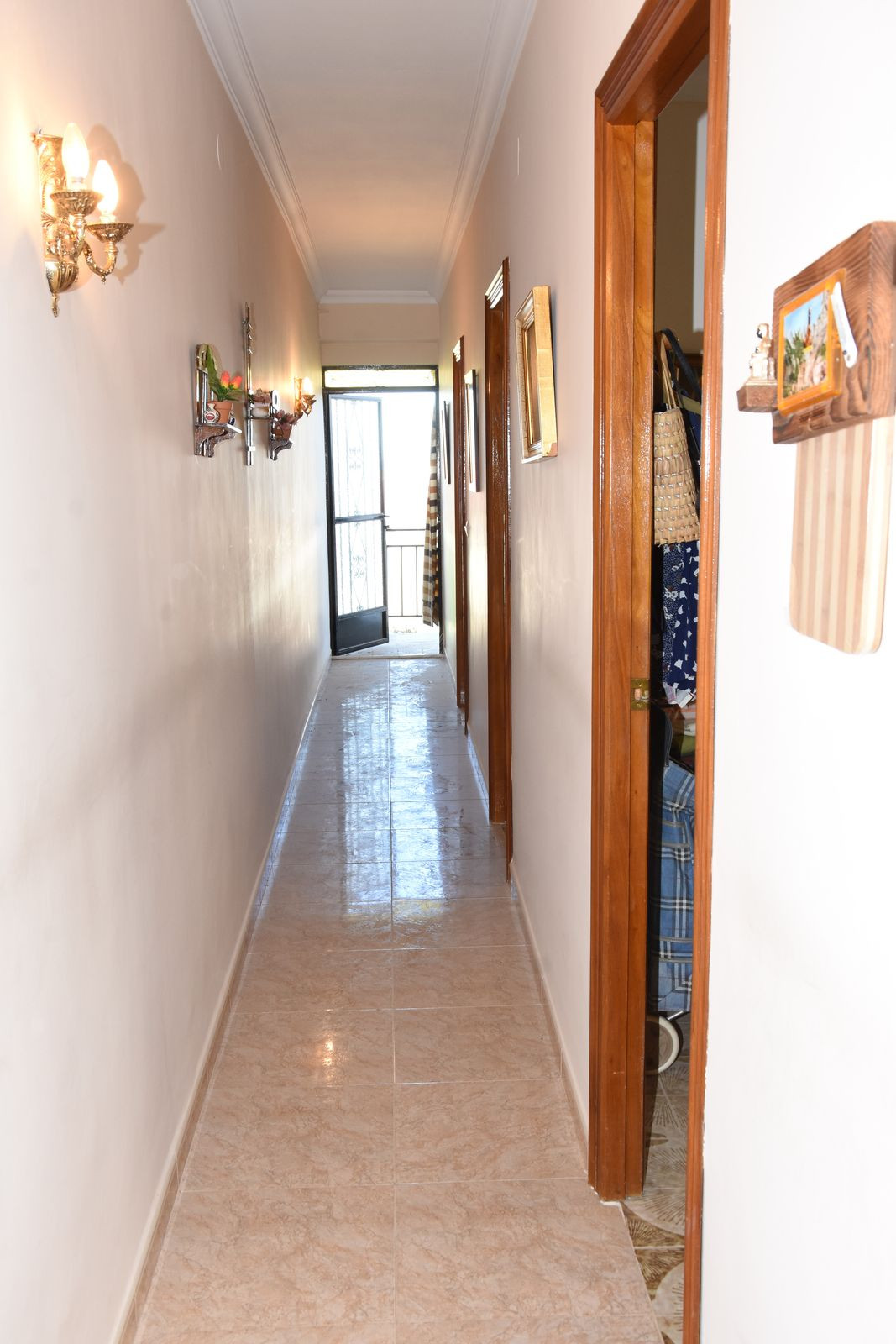 Lange hal met deuren in een appartement, leidend naar de ingang.