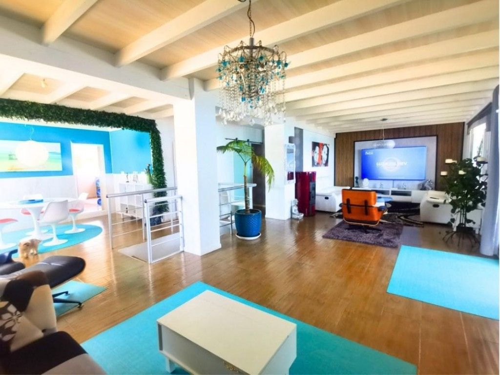 Lichte woonkamer met open plattegrond, turquoise accenten en houten vloeren.