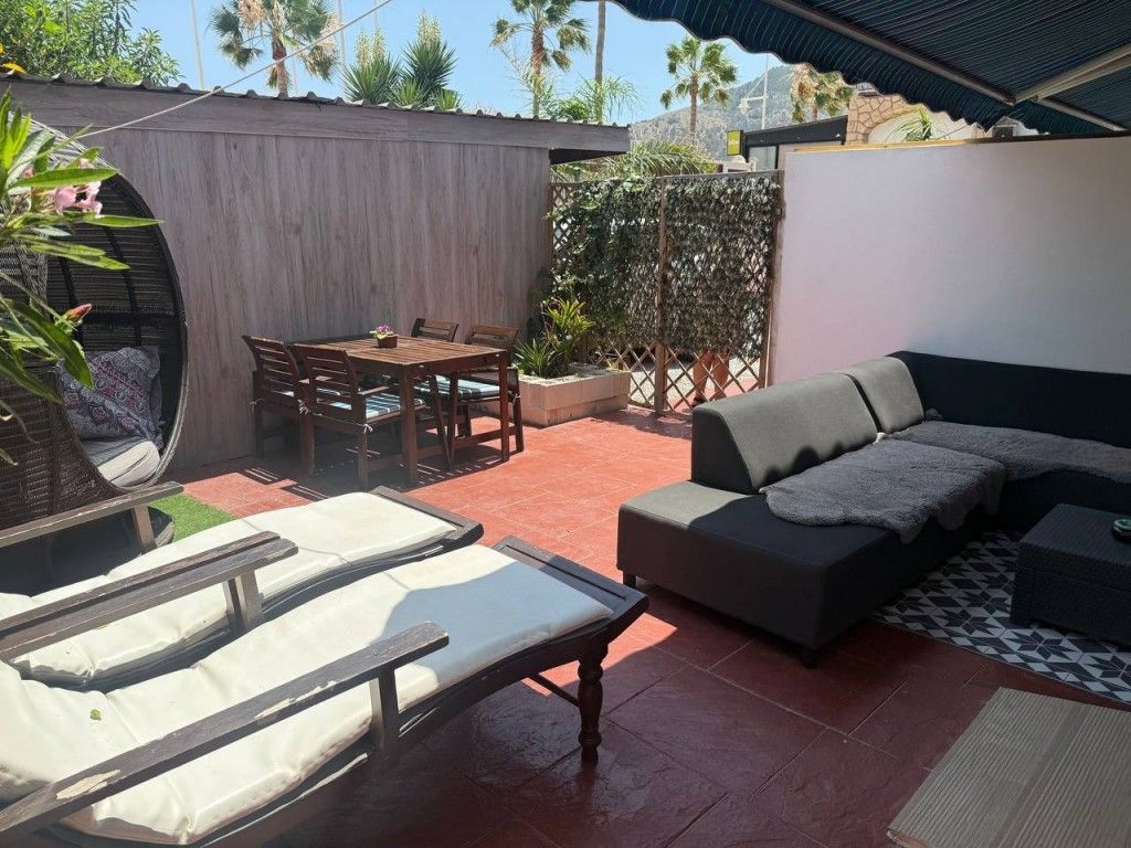 Buitenpatio met loungebank, eethoek en ligstoelen.