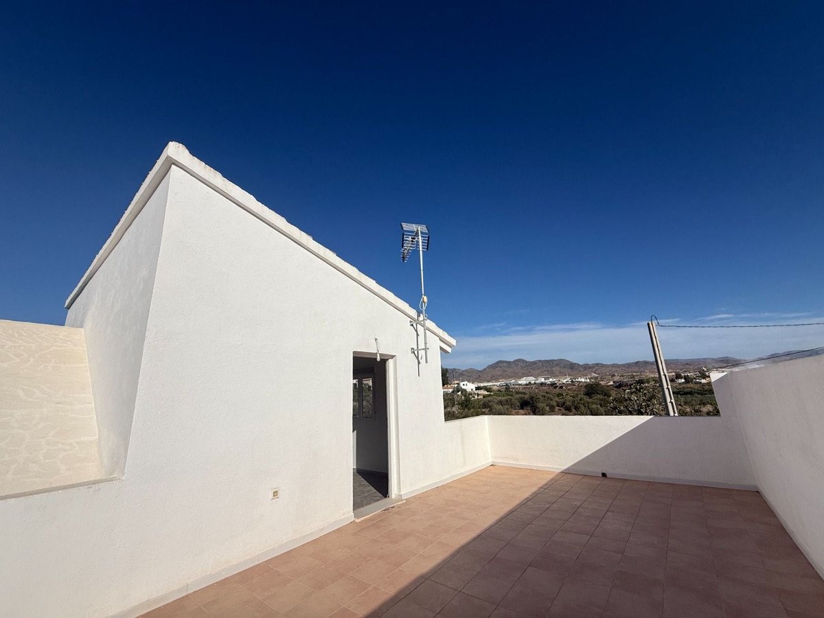 White-walled rooftop terrace with clear blue sky and distant landscape view