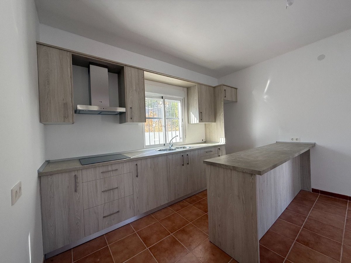 Modern kitchen with island, light wood cabinets, and a window overlooking outdoors.