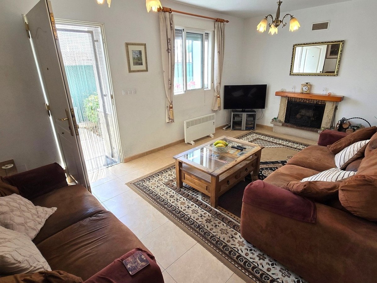 A cozy living room with a fireplace, television, comfortable sofas, and a coffee table, leading to an outdoor patio.