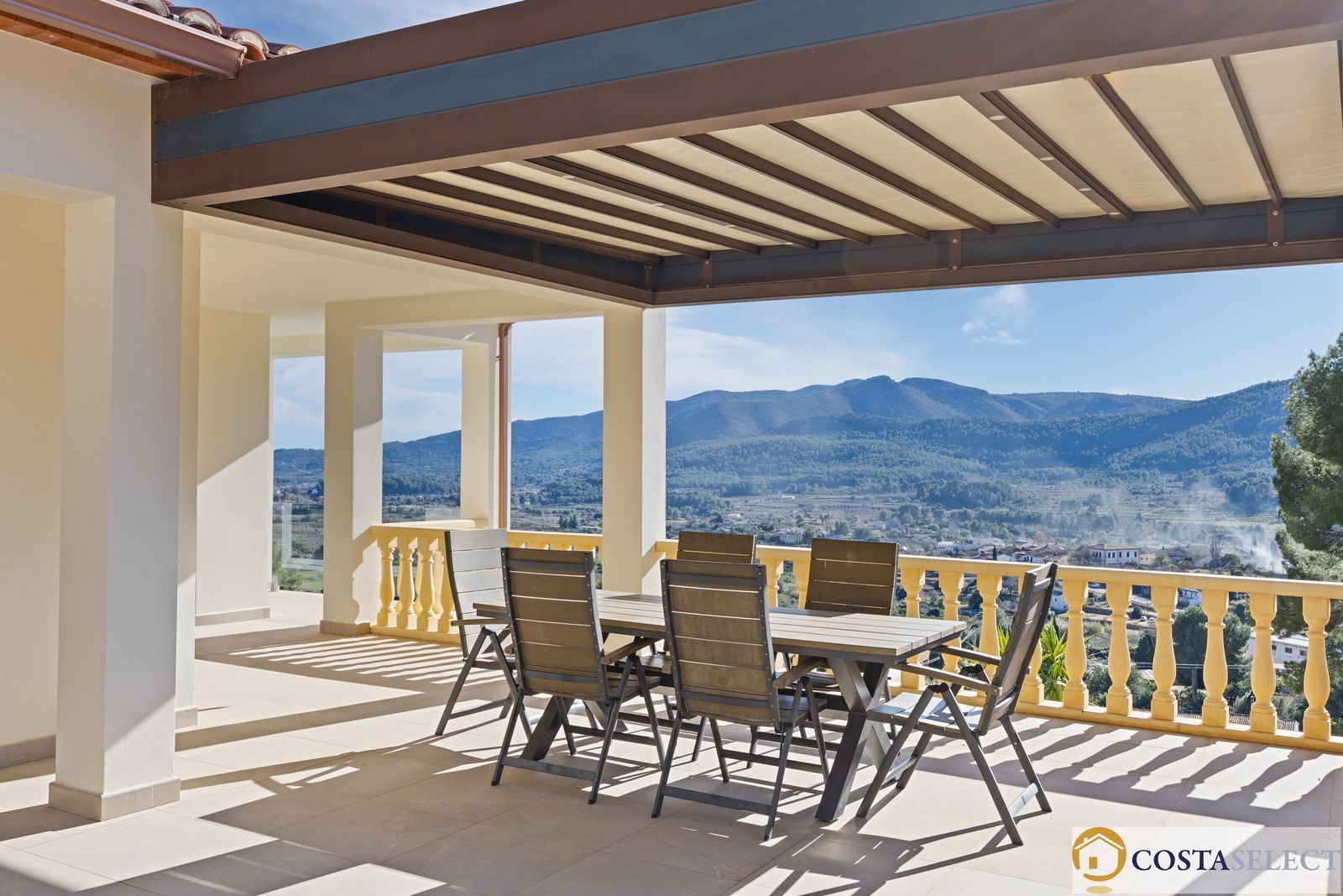 Terras met uitzicht op de bergen, tafel en stoelen op het terras.