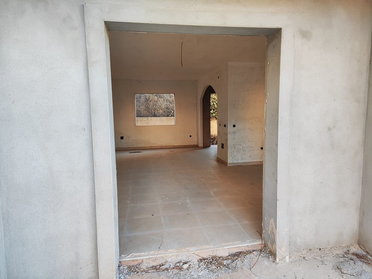 Onvoltooide interieurrenovatieproject met open doorgang en tegelvloer.