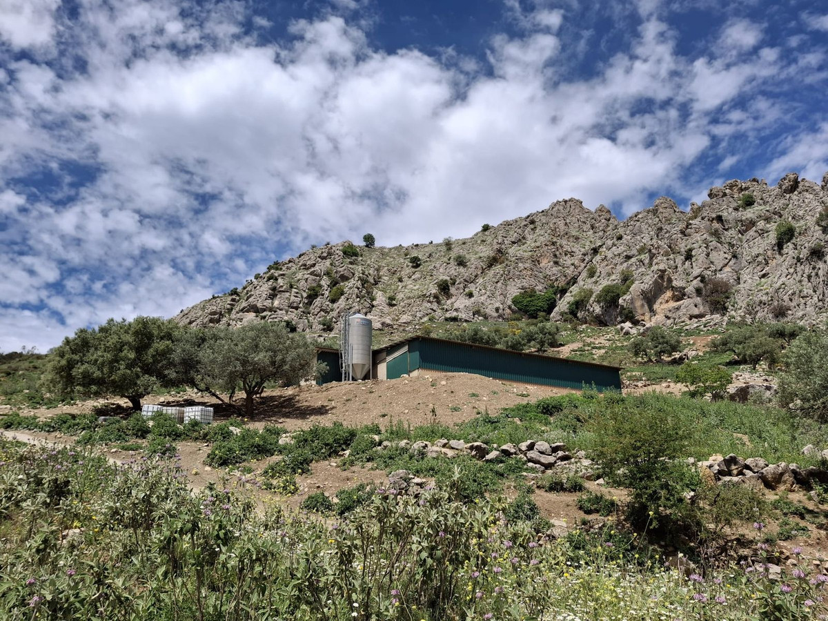 Landelijk gebouw in berglandschap met blauwe lucht en wolken.