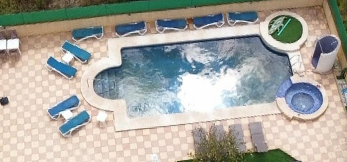 Swimming pool with multiple loungers and a small jacuzzi area