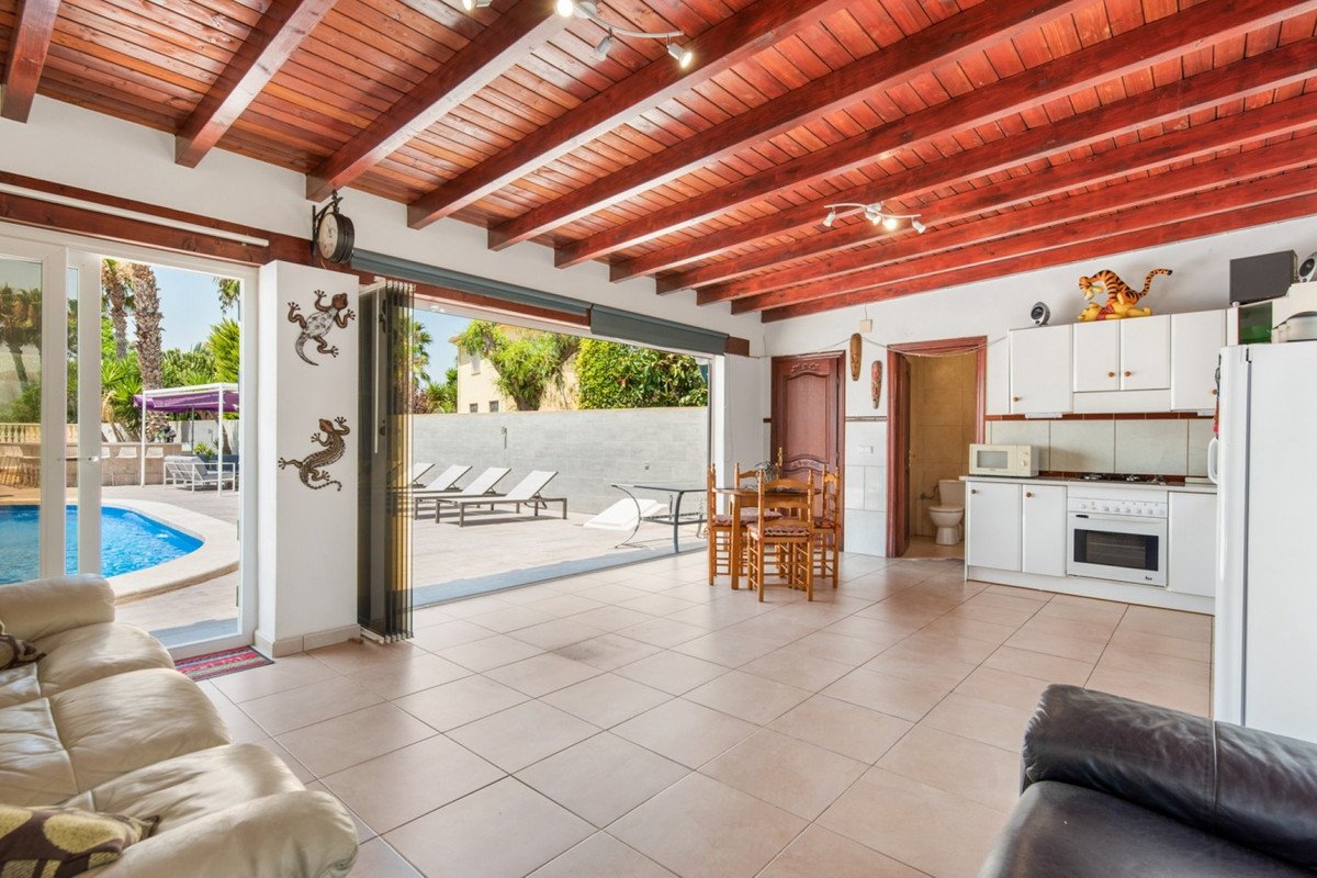 Spacious open-plan living area and kitchen with a view of the swimming pool and outdoor lounge chairs.