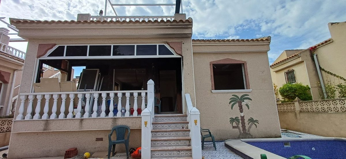 Exterior view of a house with a balcony, stairs, and a swimming pool. Palm tree decoration on the wall.