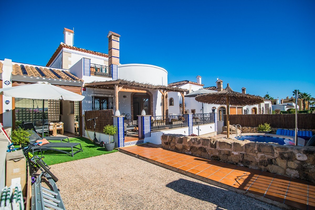 Terraced property with a small pool, sun loungers, and patio area under a clear blue sky.