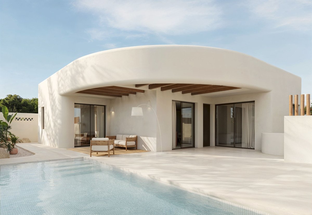 Modern villa exterior with a swimming pool, a covered terrace with outdoor seating, and large glass doors.