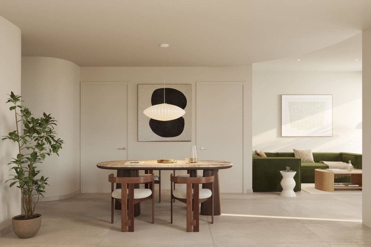 Modern dining and living area with abstract art, oval table, and green sectional sofa.