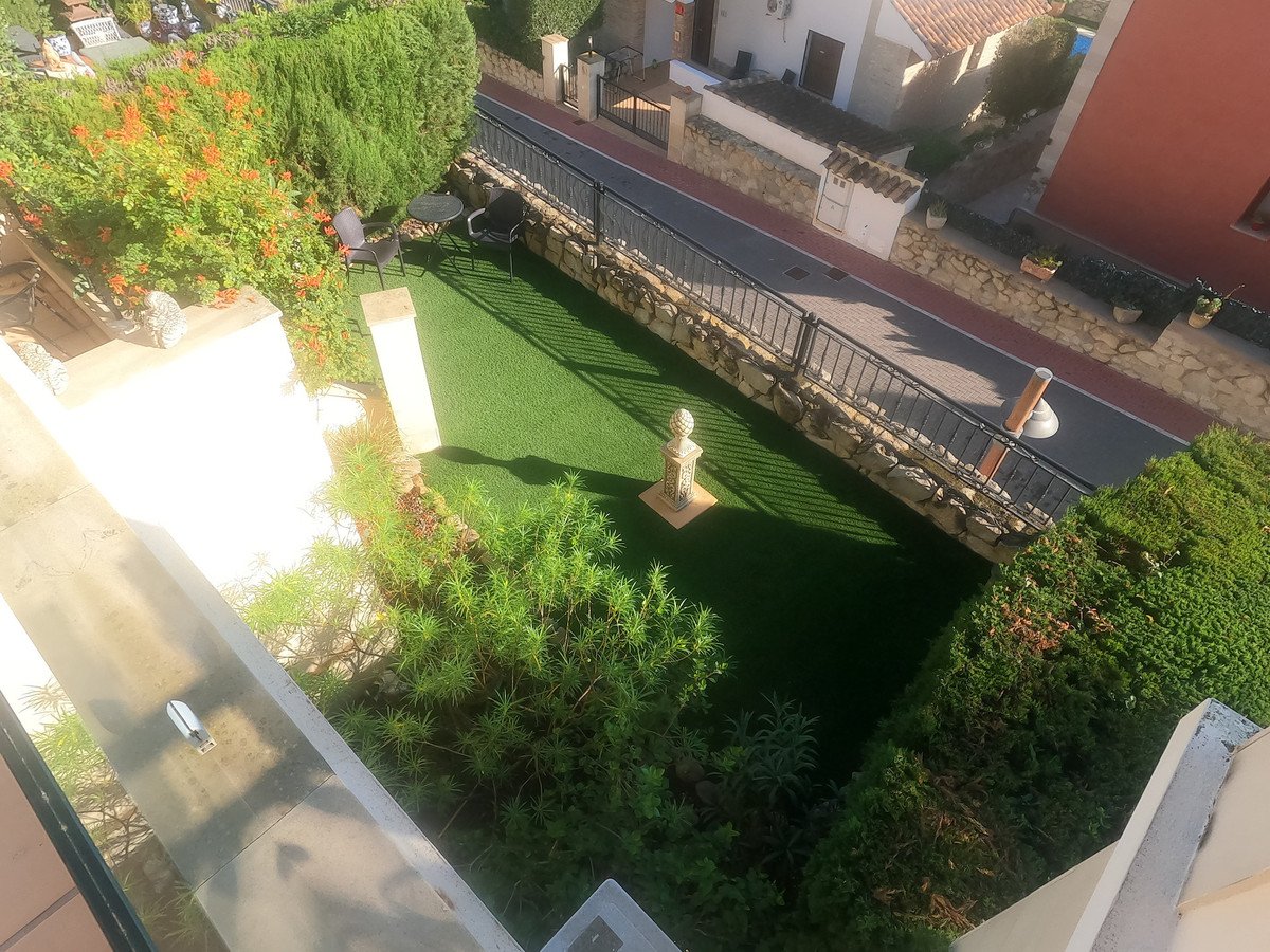Private rooftop garden with artificial grass, plants, and outdoor seating area.