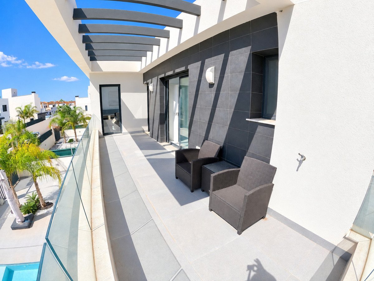 Modern balcony with two chairs, offering a view of palm trees and a swimming pool below.