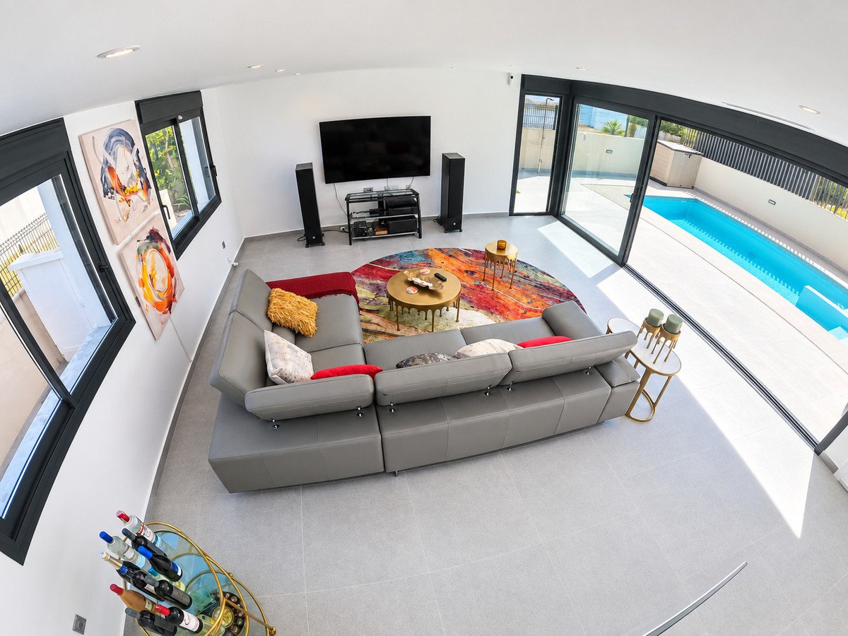 Modern living room with a large sectional sofa, colorful rug, and sliding glass doors opening to a private swimming pool.