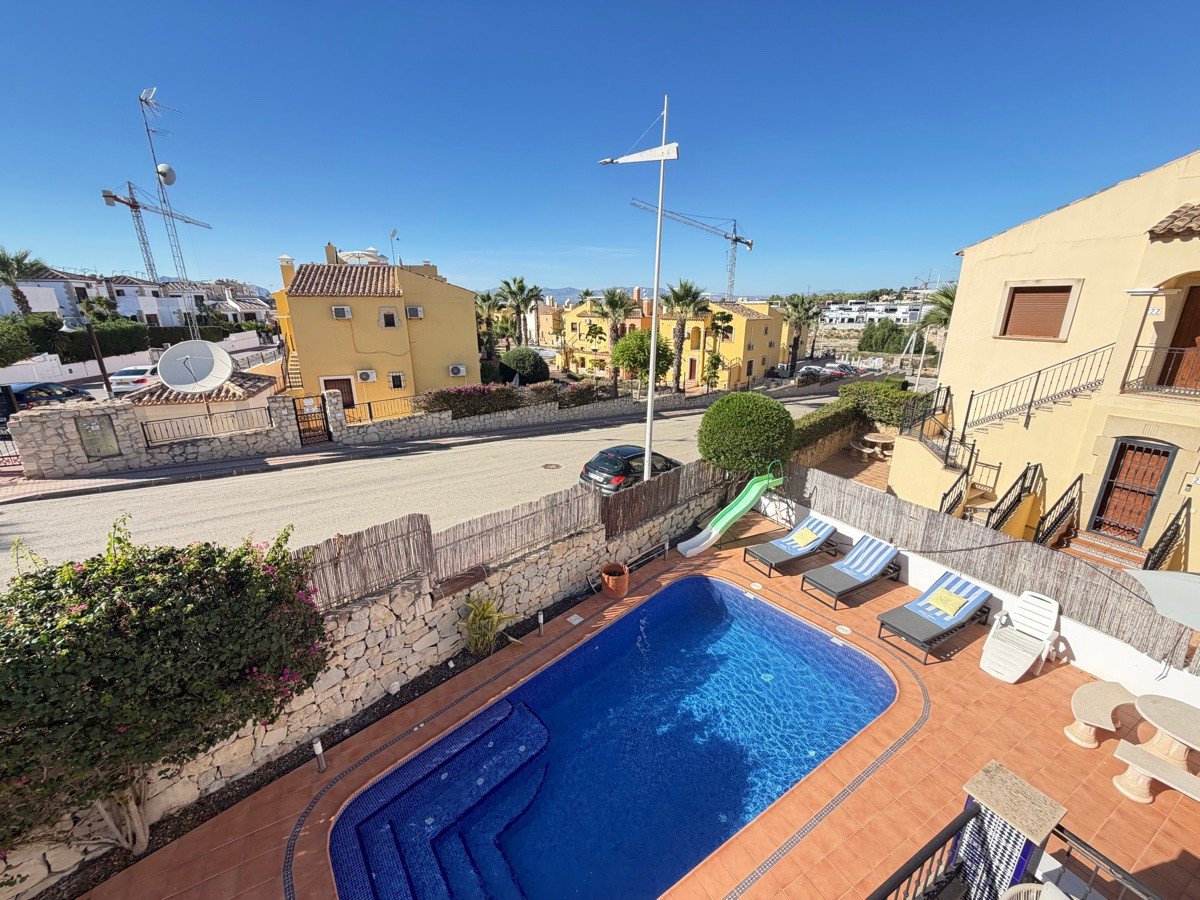 A private swimming pool with a slide, loungers, and a table and chairs on a sunny day.