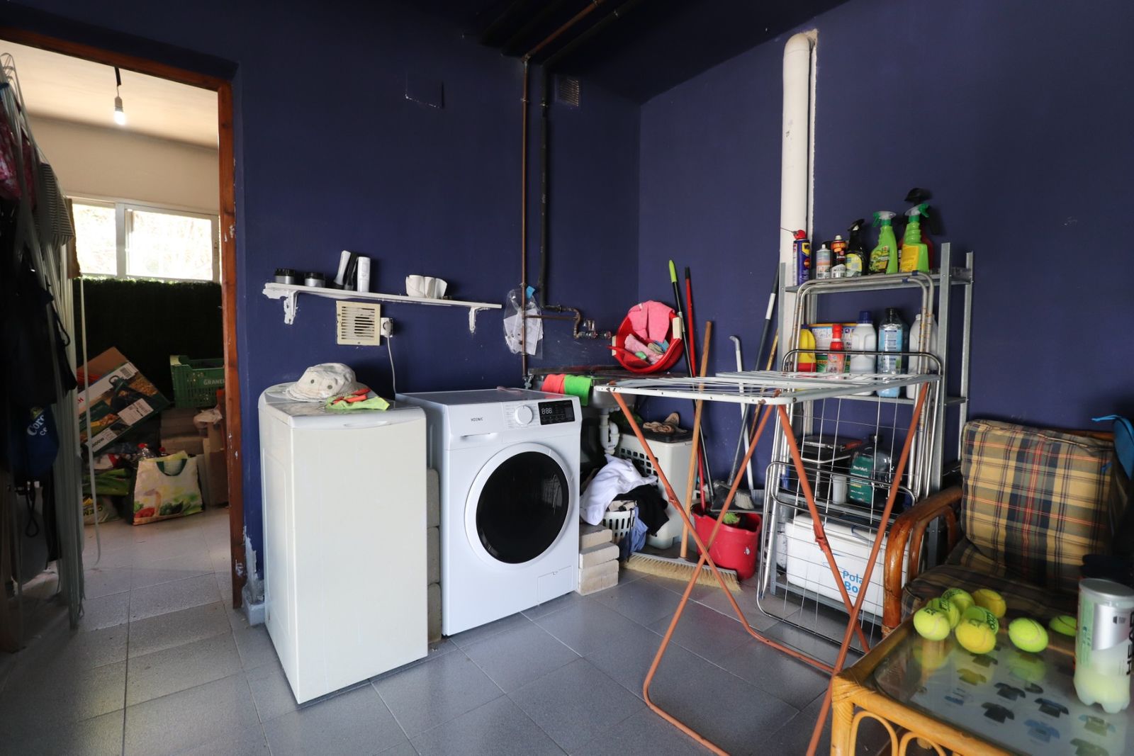 Kleine wasruimte met wasmachine, droogrek en diverse opbergoplossingen.