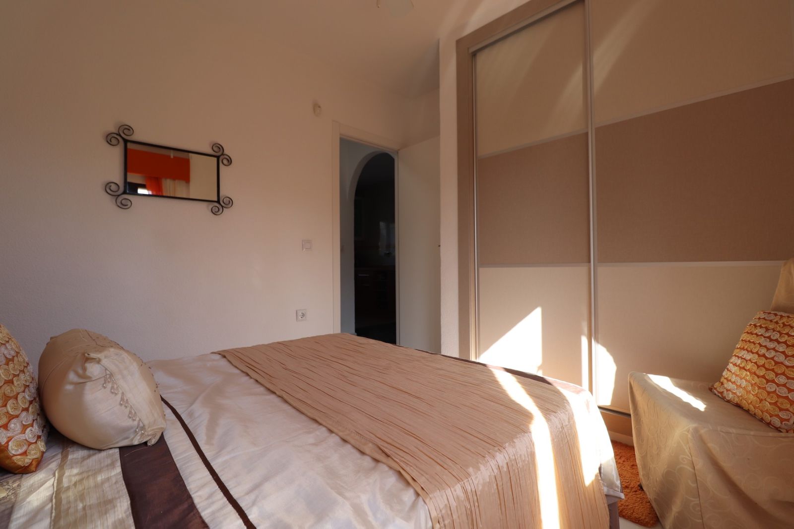 Gezellige slaapkamer met lichte kleuren en een grote schuifdeurkast.