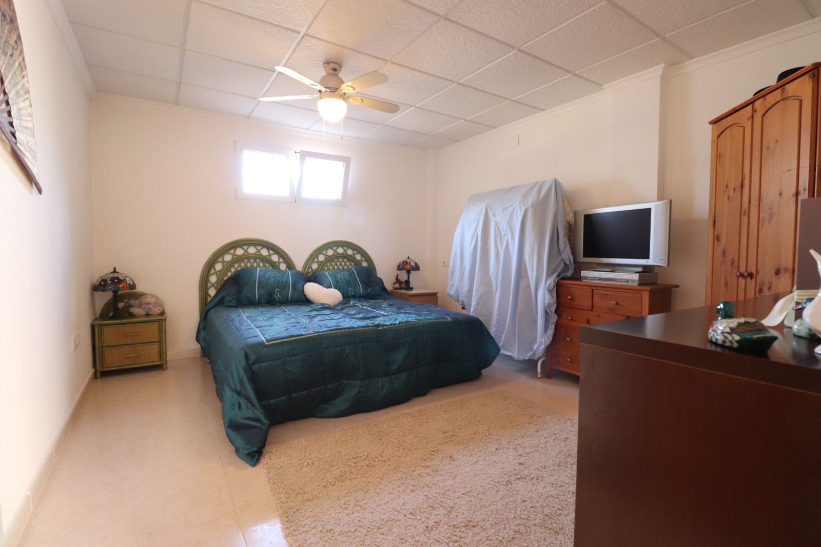 Gezellige slaapkamer met groen beddengoed en houten meubels.