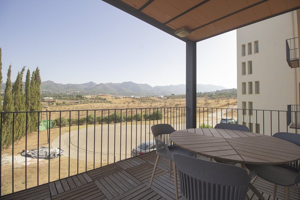 Balcony with dining set overlooks a scenic mountain landscape with dry terrain and scattered trees.