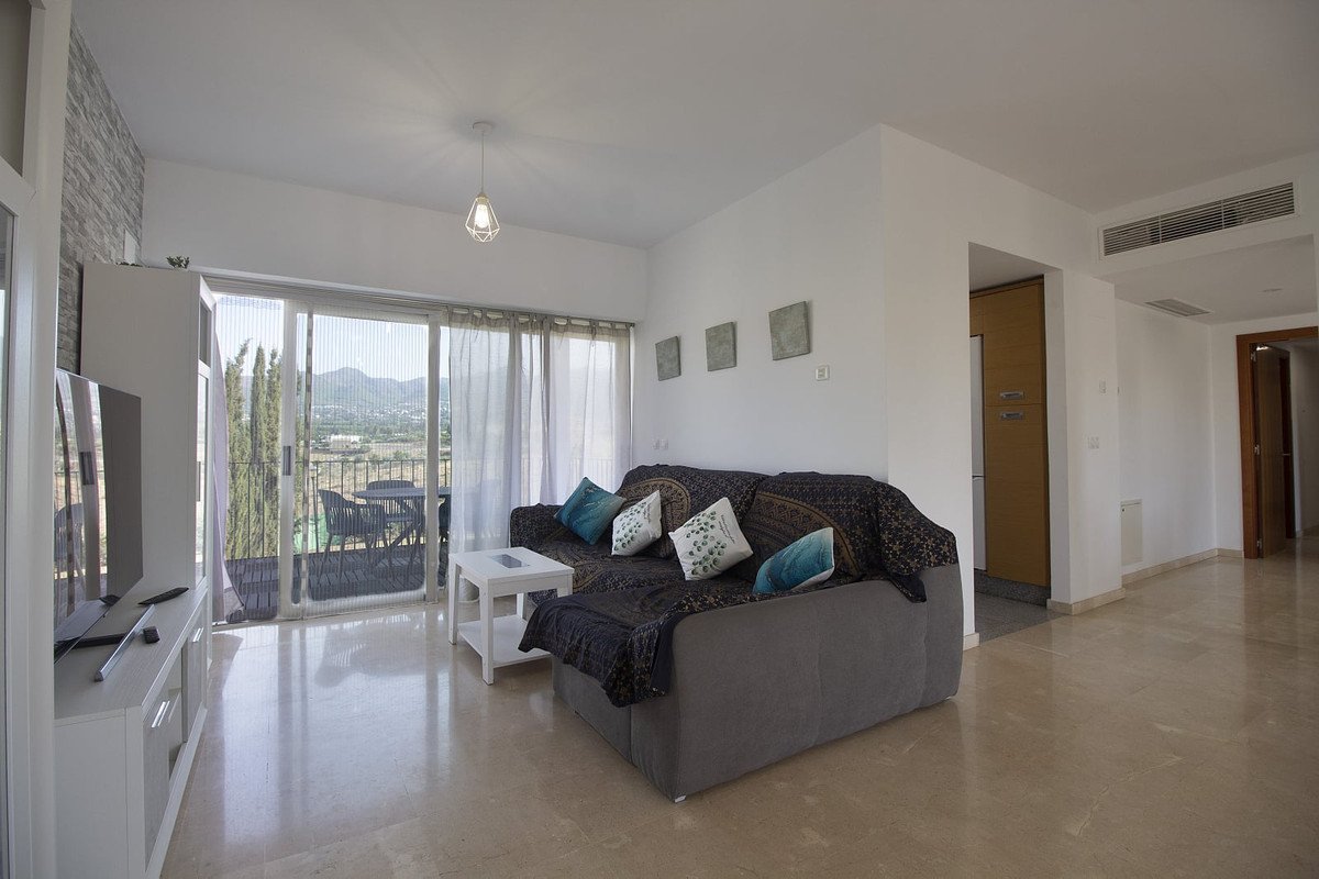 Modern living room with a comfortable sofa, large windows, and a balcony overlooking a scenic landscape.