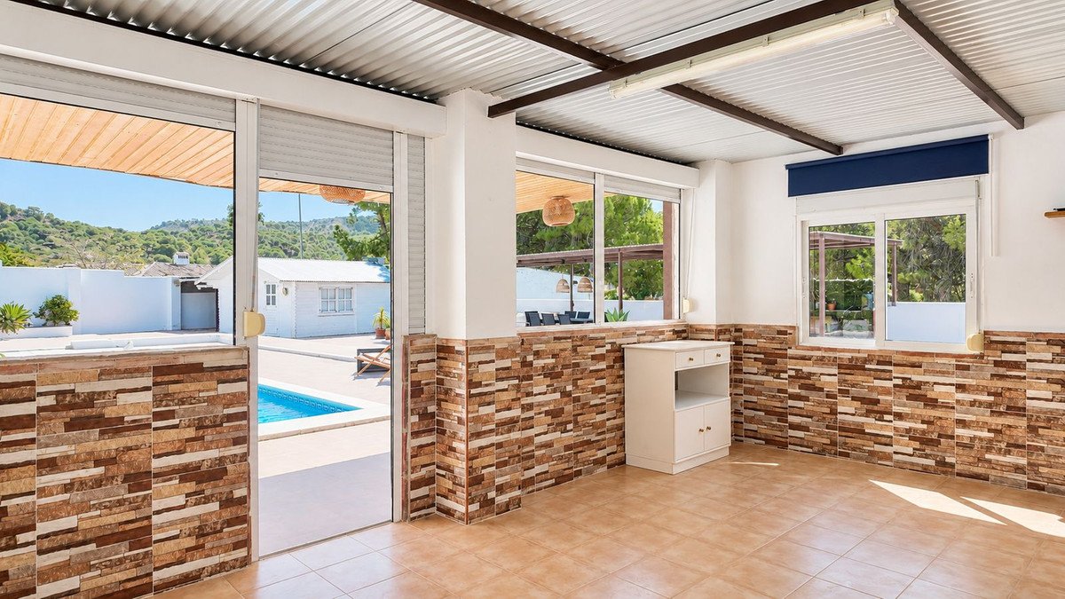 Interior room with large glass doors opening to a backyard with a swimming pool and distant hills.