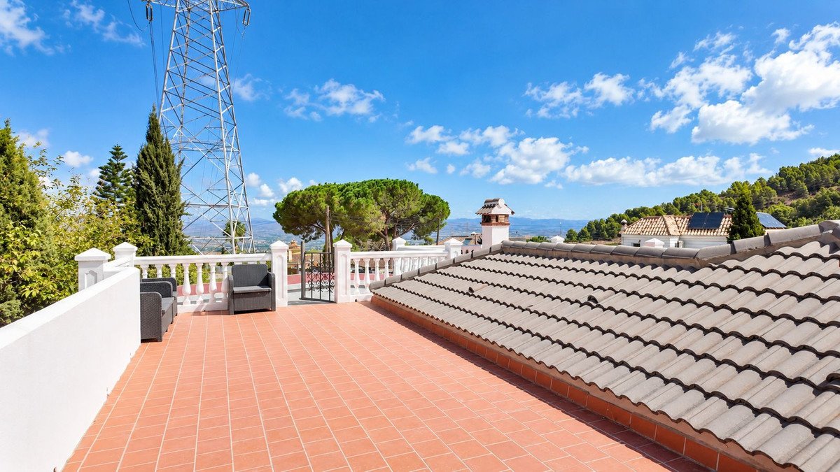 Spacious terracotta tiled terrace with outdoor seating, offering panoramic mountain views under a blue sky.