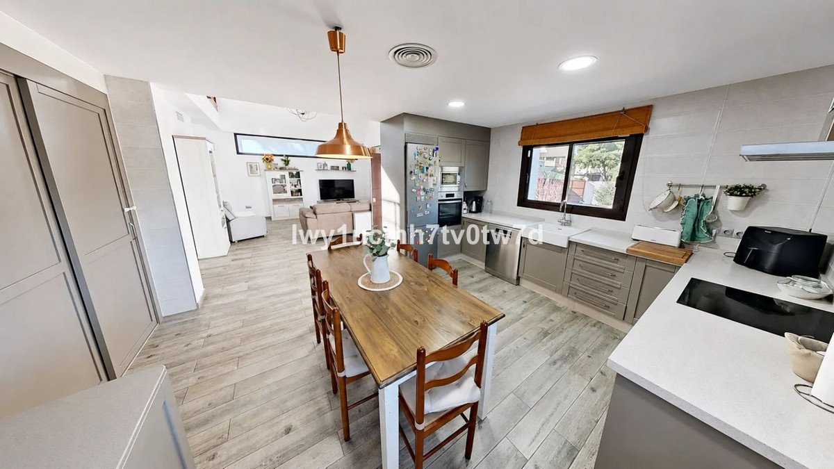 Modern kitchen with dining table, gray cabinets, and open layout to living area.