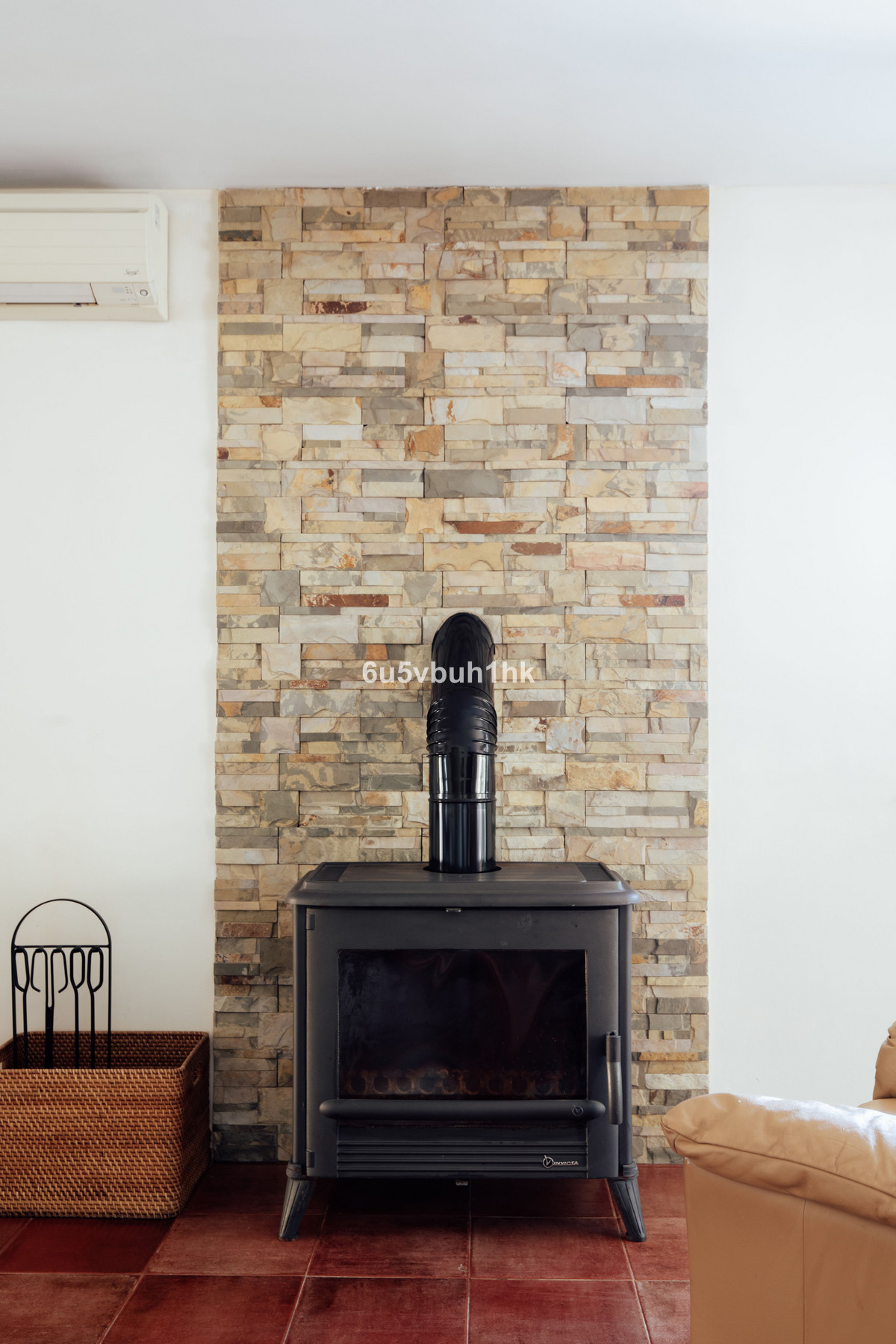 Zwarte houtkachel met stenen achterwand in een kamer.