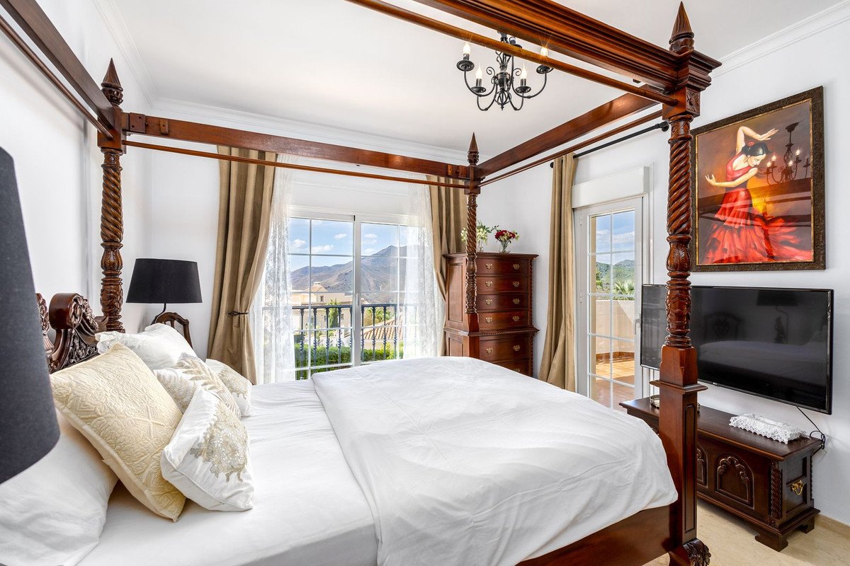 Luxurious bedroom with a four-poster bed, offering a stunning mountain view through large glass doors.