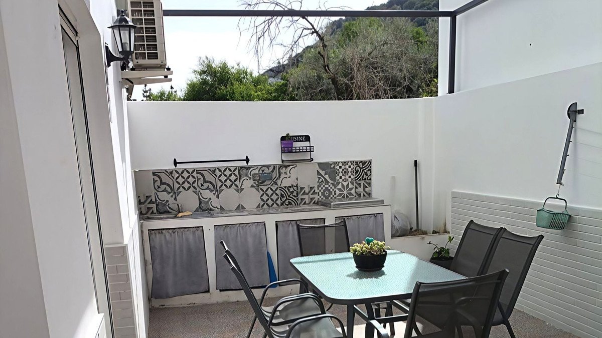 Balcony with table, chairs, and decorative wall tiles overlooking greenery