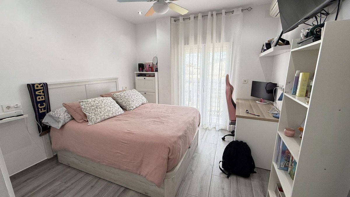 Neat bedroom with bed, desk, shelves, and natural light from window