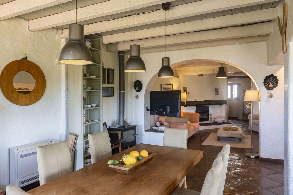 Rustic dining area with wooden table and chairs, leading to a cozy living area with a fireplace and sofa.