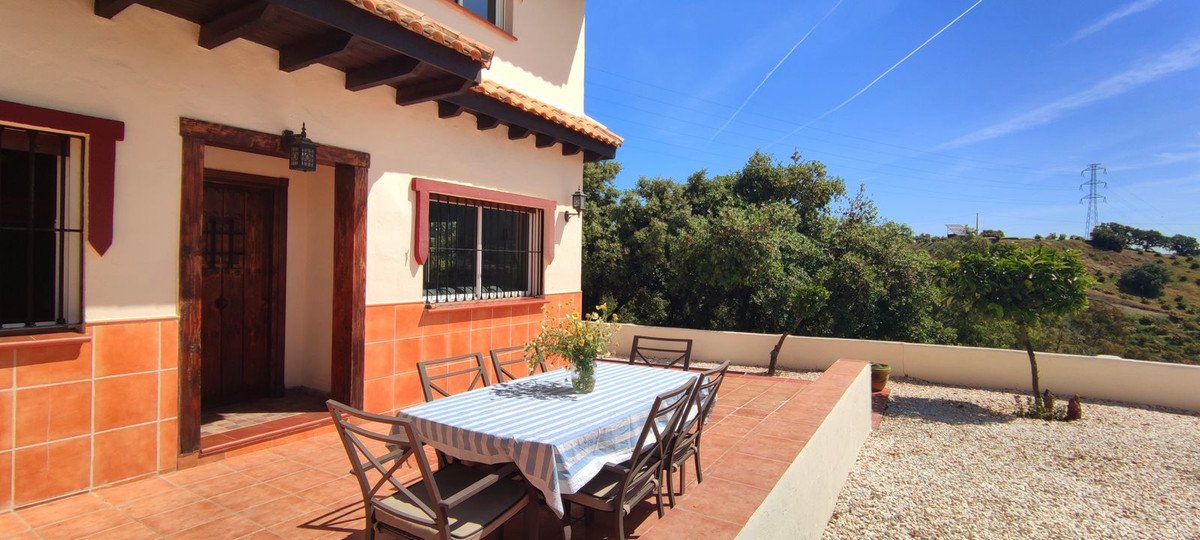 Terrace with dining table and scenic view of green hills and clear blue sky