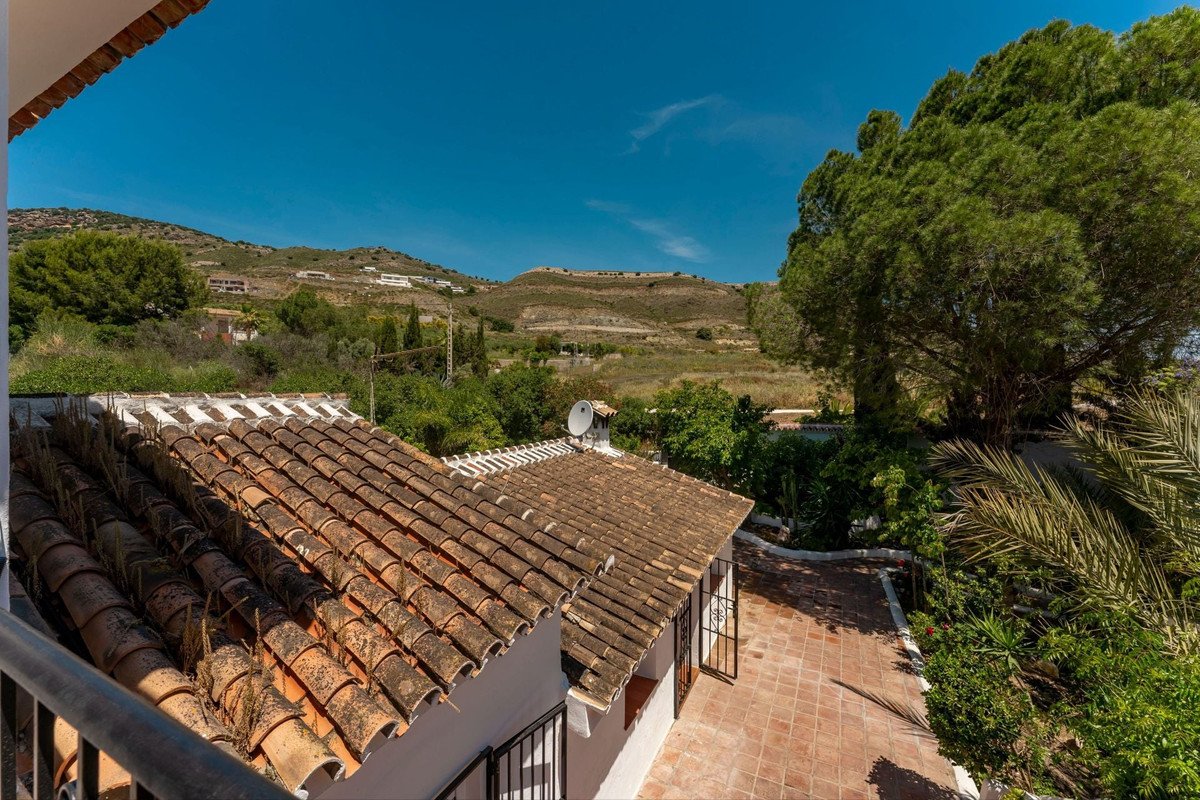 Terrace with tiled roof overlooking lush green hills and clear blue sky