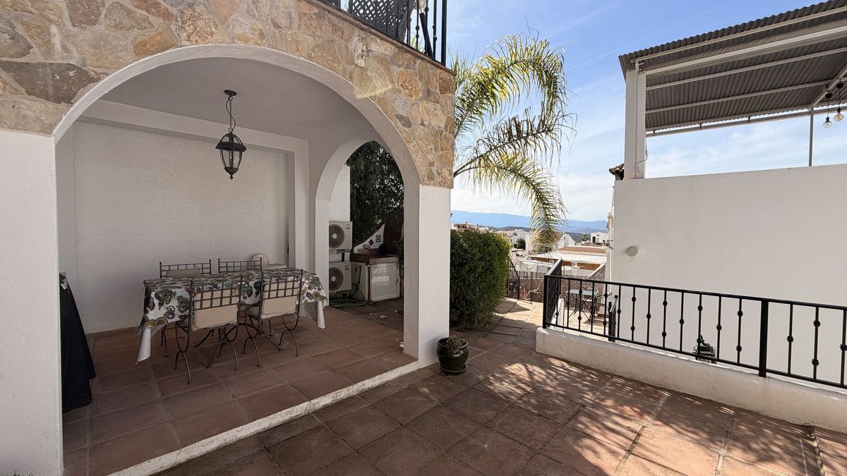 Covered patio with arched stone entry, dining table, and mountain views.