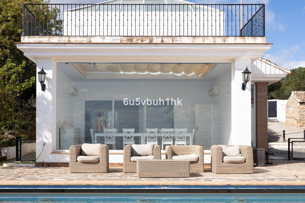 Modern villa with glass-walled living area, wicker furniture, and poolside terrace.