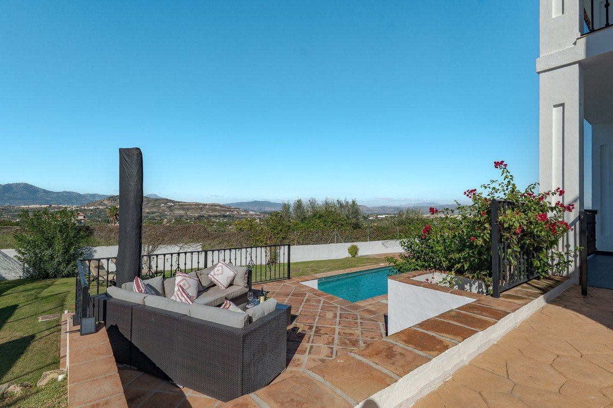 Terrace with pool, outdoor seating, and mountain views under clear blue sky.