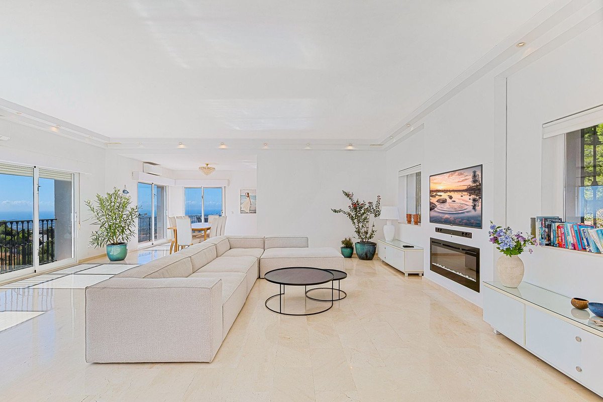 Spacious living room with a large sectional sofa, modern fireplace, television, and stunning ocean views from the balcony.