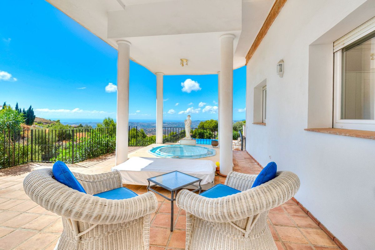 Terrace with jacuzzi, seating area, and stunning panoramic sea and landscape views under a bright blue sky.